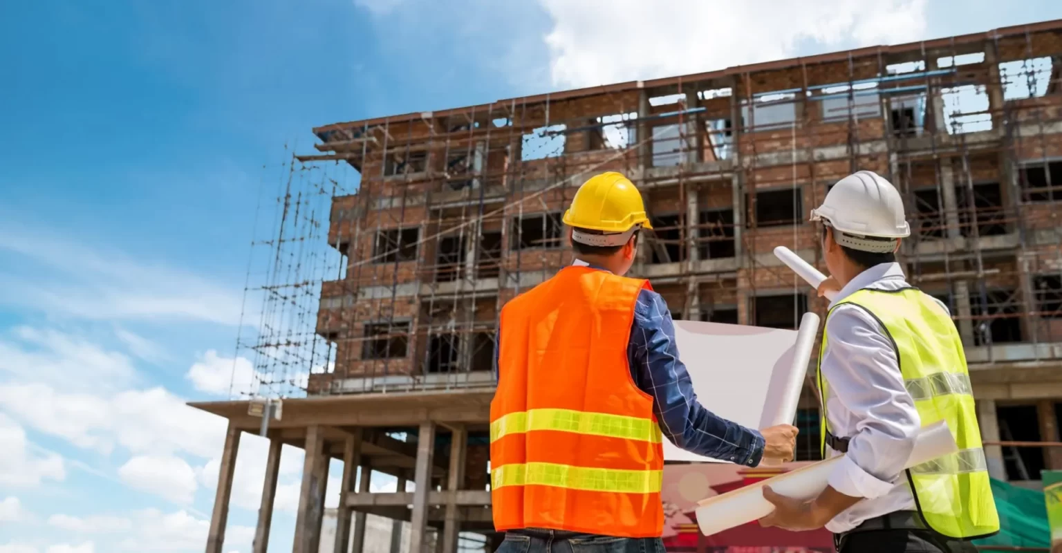 Chefs de chantier devant un immeuble en construction, assurance promoteur et dommages-ouvrage