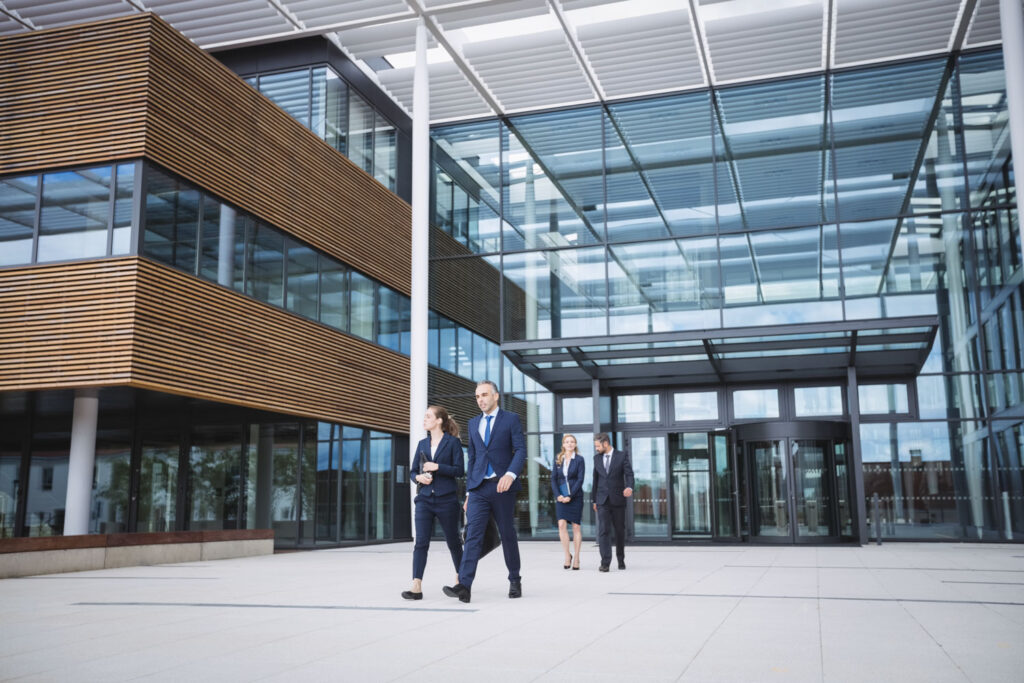 Collaborateurs devant un immeuble de bureaux, assurance des sociétés de services et de conseil